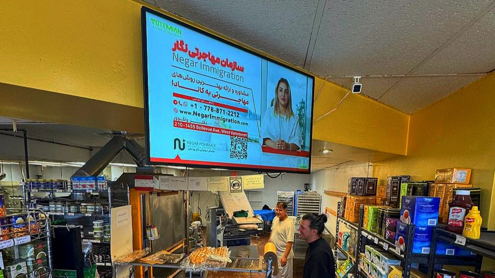 A digital brandboard displaying an advertisement for Totemian Negar Immigration in a commercial